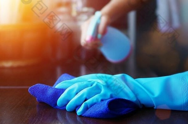 手蓝色的橡胶手套持有蓝色的超细纤维清洁布喷雾瓶消毒解决方案使清洁消毒好