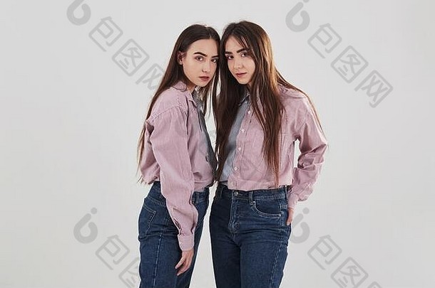 姐妹双胞胎站摆姿势工作室白色背景