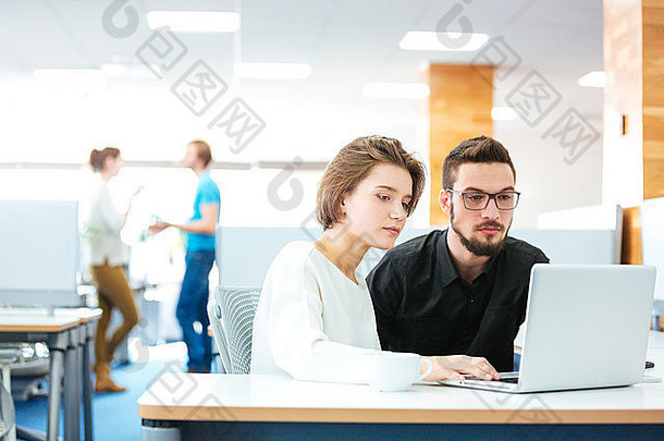 集中年轻的男人。女人坐着工作移动PC办公室