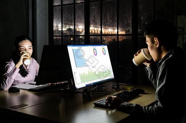 年轻的成人亚洲商人女人喝热咖啡工作晚些时候晚上办公室桌面电脑移动PC硬