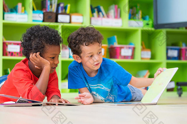 男孩孩子躺地板上阅读演讲书学前教育图书馆幼儿园学校教育概念