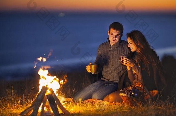 肖像快乐夫妇坐着火秋天海滩