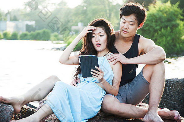 亚洲夫妇坐着女人阅读电子阅读器