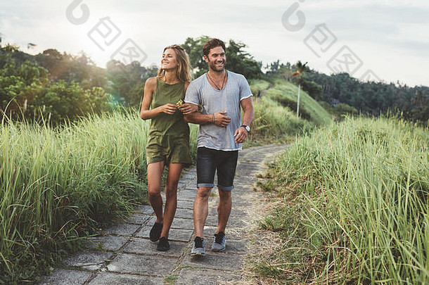 户外拍摄年轻的夫妇爱走通路草场男人。女人走高草场
