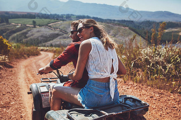 后视图拍摄年轻的夫妇骑四自行车农村微笑女人坐着的男朋友