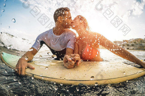 快乐运动型夫妇接吻冲浪海洋冲浪者持有手冲浪板温柔的时刻
