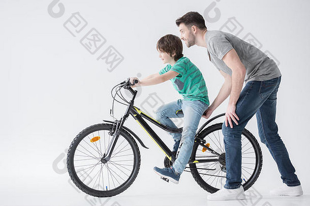 父亲帮助儿子骑自行车白色