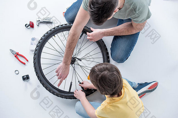 开销视图儿子父亲修复自行车轮胎工作室白色