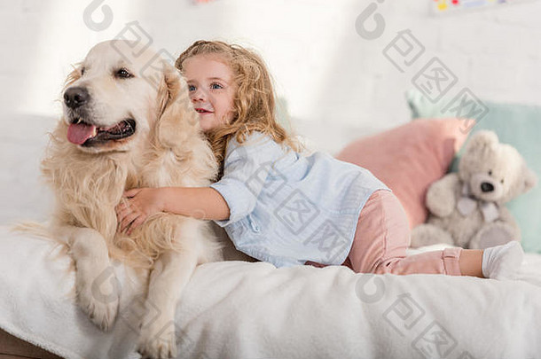 可爱的孩子拥抱金寻回犬狗床上孩子们房间
