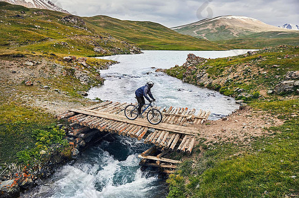 男人。山自行车穿越河木桥山谷