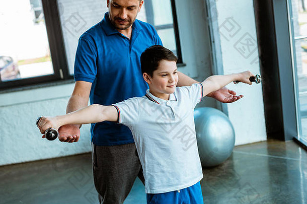 父亲帮助儿子锻炼哑铃体育中心