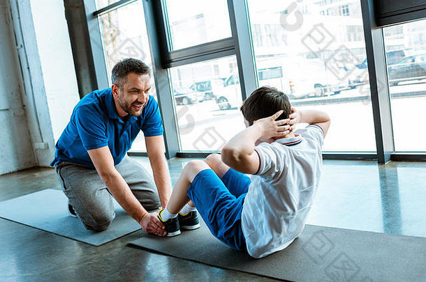 父亲帮助儿子坐锻炼健身房