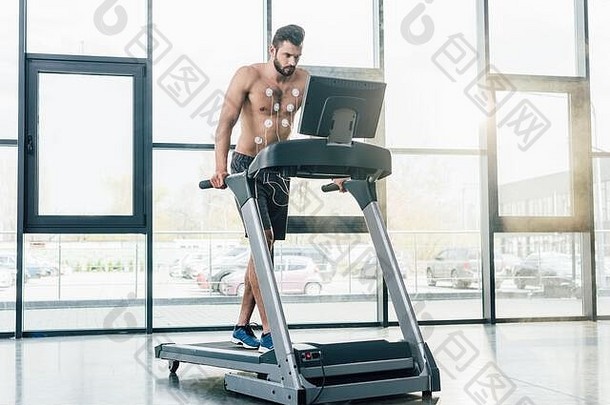 英俊的赤膊上阵运动员电极运行跑步机耐力测试健身房
