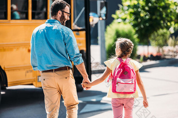 后视图父亲女儿持有手走学校公共汽车
