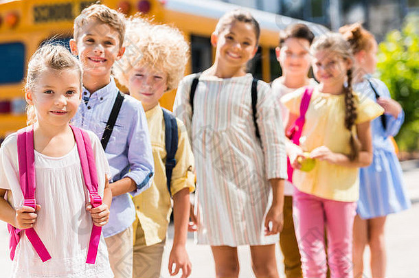 集团可爱的小学生站行前面学校公共汽车相机