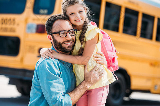 英俊的父亲拥抱女儿前面学校公共汽车