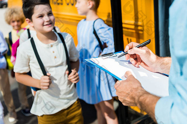 裁剪拍摄老师写作列表剪贴板学生进入学校公共汽车模糊背景