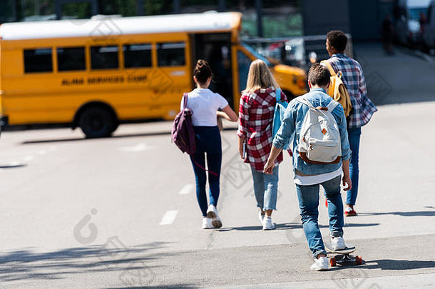 后视图集团青少年学者走学校公共汽车停车