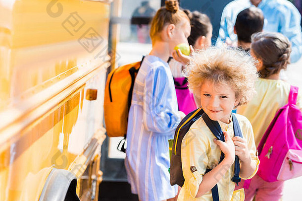 快乐卷曲的小学生同学们站学校公共汽车
