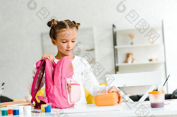 可爱的女学生持有午餐盒子粉红色的背包