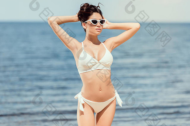 有吸引力的女人摆姿势太阳镜白色比基尼海度假胜地