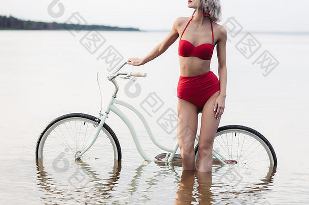 裁剪视图女孩红色的比基尼摆姿势自行车水