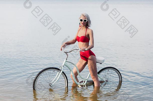 优雅的女孩红色的古董比基尼摆姿势自行车水