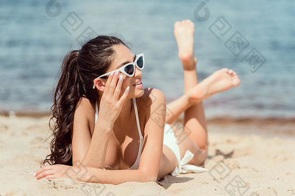 有吸引力的年轻的女人太阳镜比基尼放松海滩海