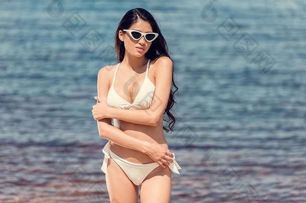 苗条的浅黑肤色的女人女人摆姿势太阳镜白色泳衣海