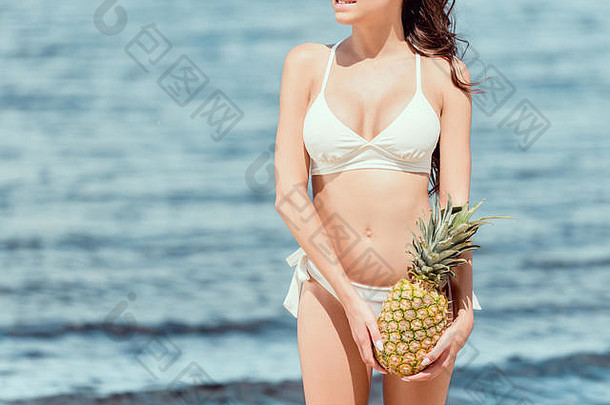 裁剪视图女人白色泳衣持有菠萝海