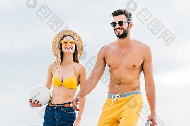 美丽的年轻的夫妇海滩衣服排球球前面多云的天空