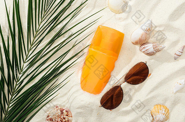 橙色瓶防晒霜沙子贝壳绿色棕榈叶时尚的太阳镜