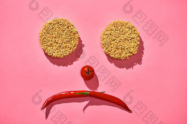 食物概念脸使热辣椒Tomatos面条粉红色的背景