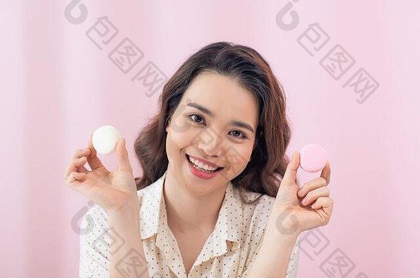 关闭年轻的亚洲女人吃蛋糕马卡龙粉红色的背景