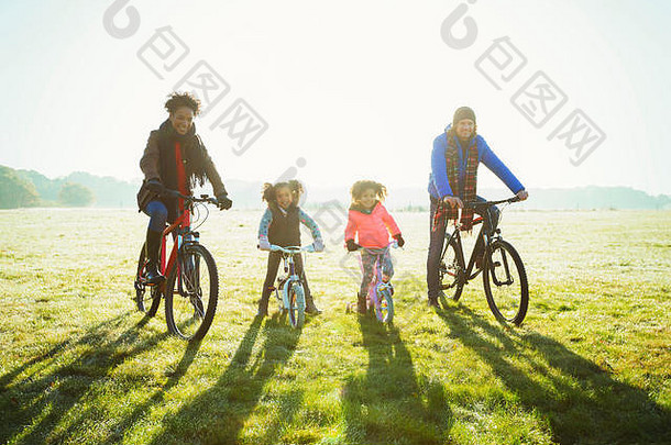 肖像年轻的家庭自行车骑阳光明媚的秋天公园草