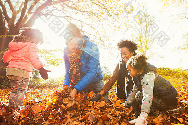 年轻的家庭玩秋天叶子阳光明媚的公园