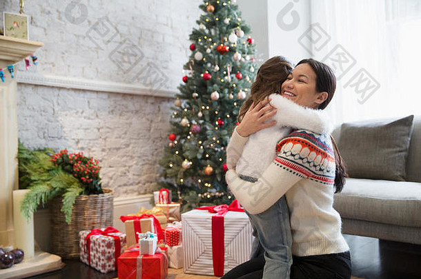 妈妈。女儿拥抱圣诞节树礼物生活房间