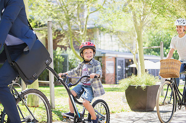 肖像微笑男孩头盔骑串联自行车父亲公园