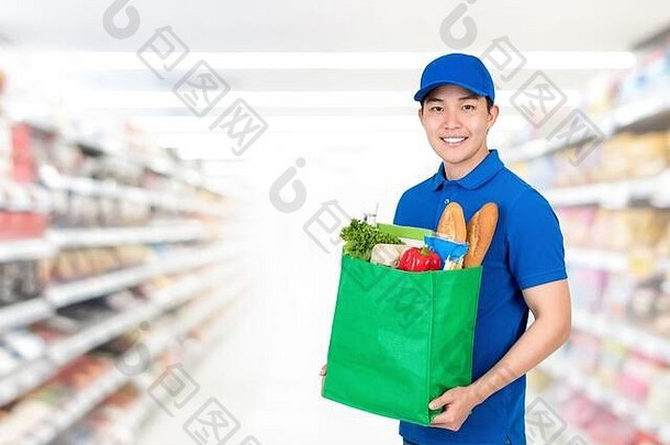 微笑英俊的亚洲男人。持有杂货店购物袋超市背景食物交付服务概念