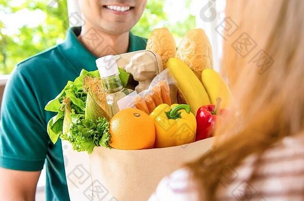 微笑交付男人。给杂货店袋女人客户首页在线食物购物服务概念
