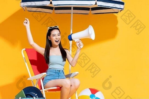 狂喜的年轻的亚洲女人夏天海滩装持有宣布扩音器阳光明媚的黄色的孤立的工作室背景