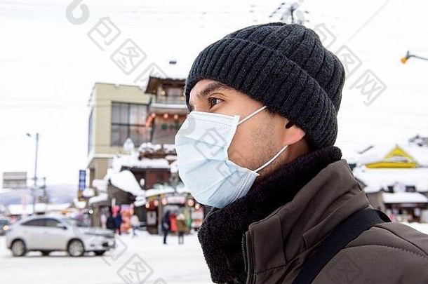 亚洲旅游男人。穿面具保护冠状病毒走在户外冬天北海道日本