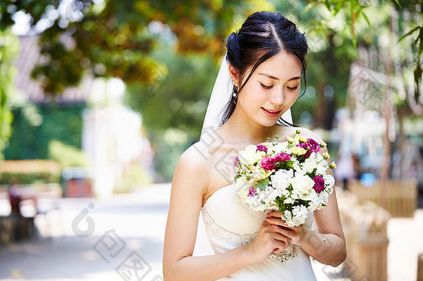 美丽的快乐年轻的亚洲新娘穿新娘面纱持有群花