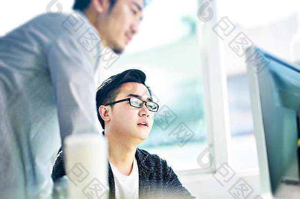 年轻的亚洲商人讨论前面桌面电脑办公室