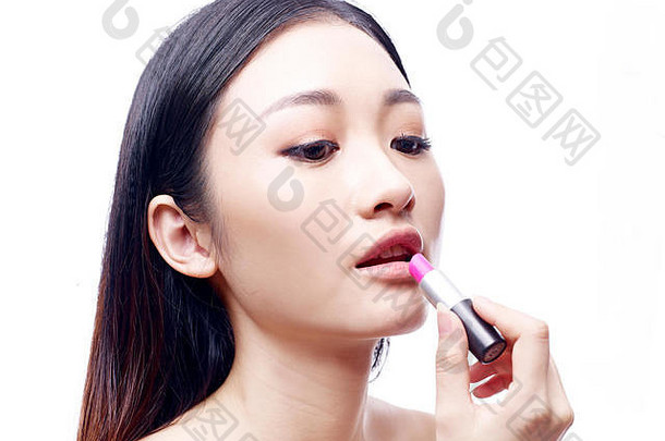 年轻的美丽的亚洲女人应用粉红色的口红孤立的白色背景