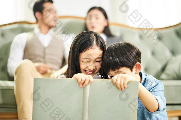 亚洲孩子们哥哥妹妹坐着地毯阅读书家庭生活房间父母坐着沙发上背景