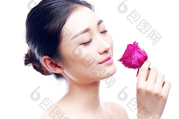 年轻的美丽的亚洲<strong>女人</strong>享受香味红色的<strong>玫瑰</strong>孤立的白色背景