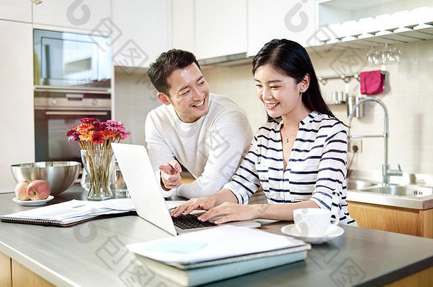 快乐年轻的亚洲夫妇工作首页会说话的讨论移动PC电脑厨房