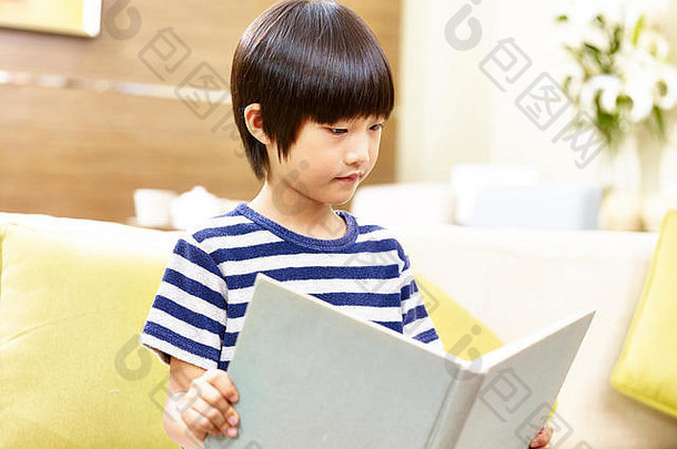 岁的亚洲男孩坐着沙发上阅<strong>读书</strong>首页