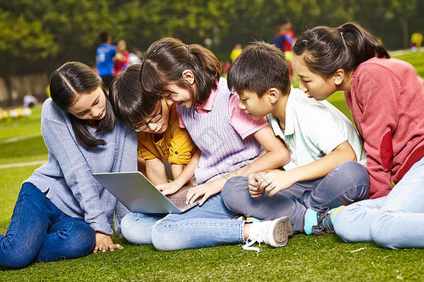 集团亚洲小学学校孩子们坐着草移动PC电脑